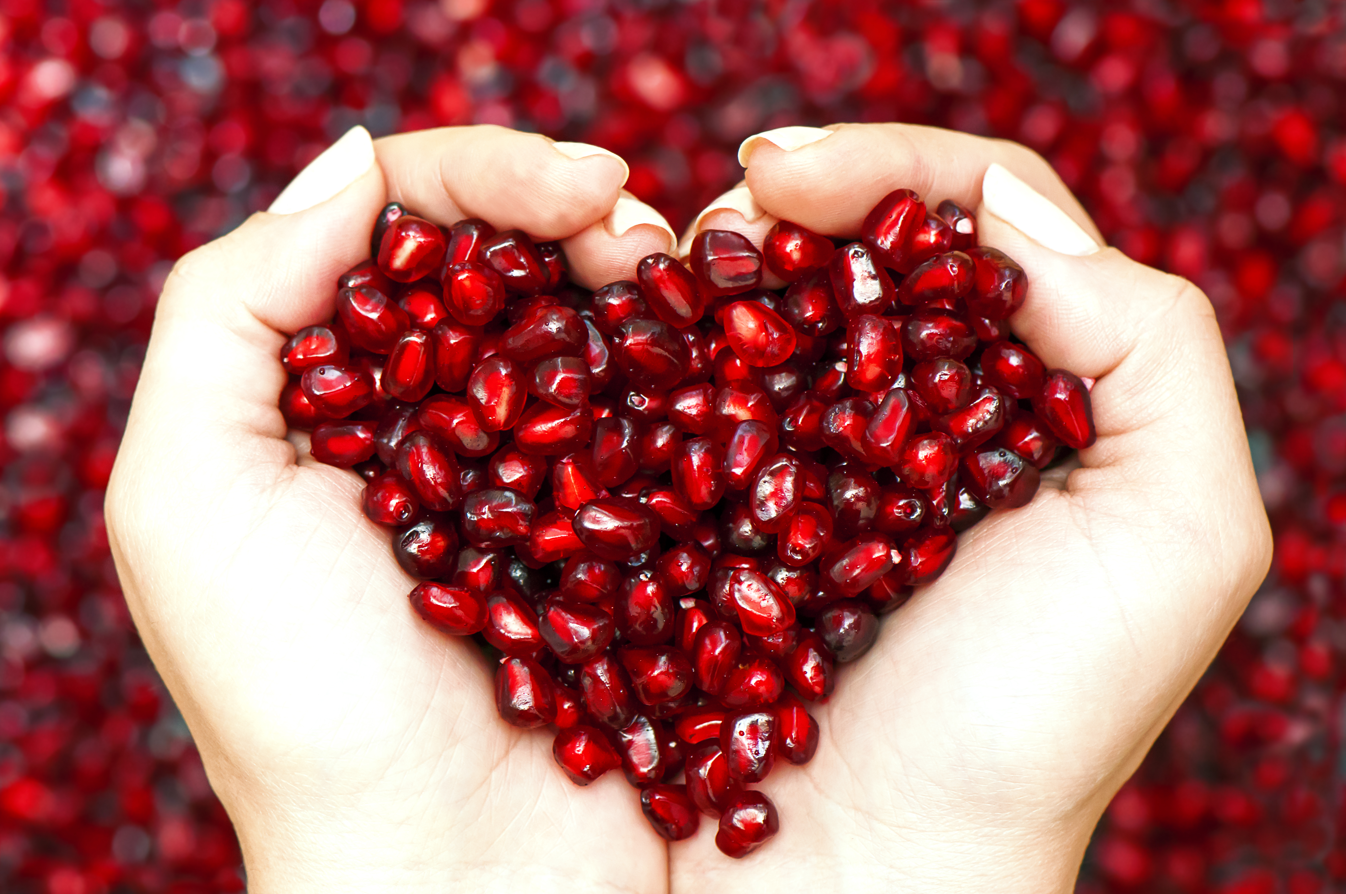 pomegranate seeds in heart-shaped hands