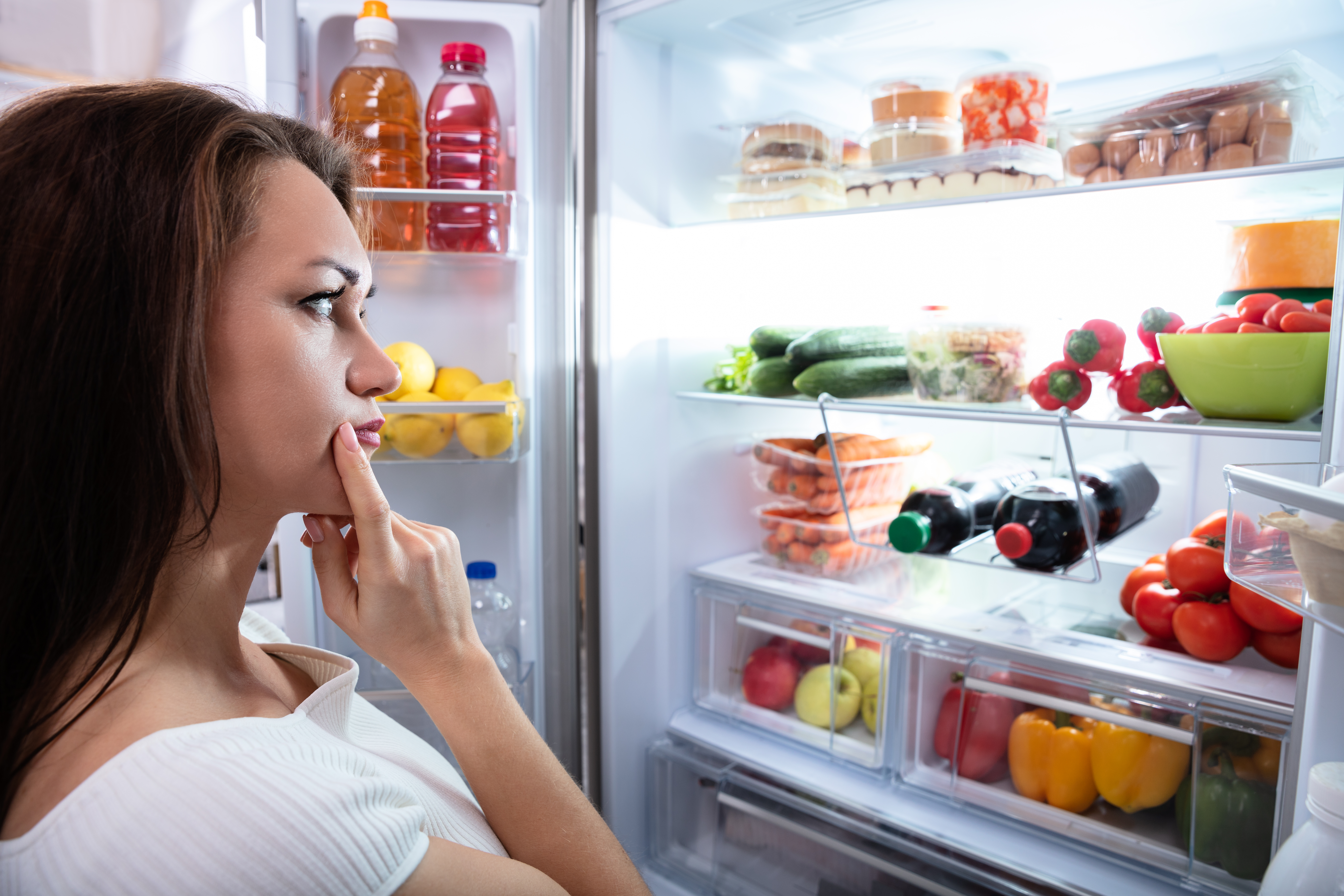 puzzled woman in front of refrigerator